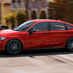 Red sedan driving on city street